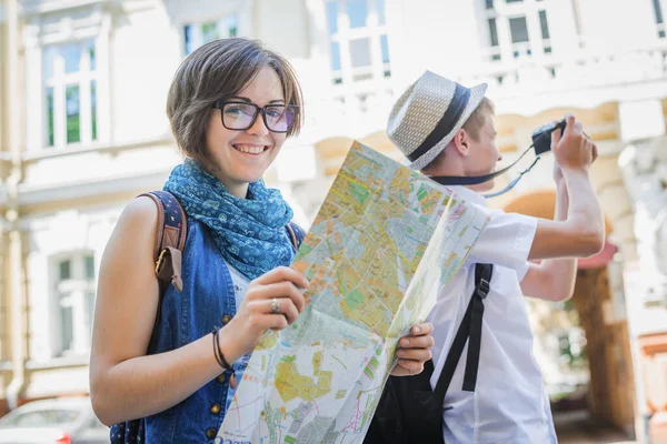 Trendy young couple in town with touristic map