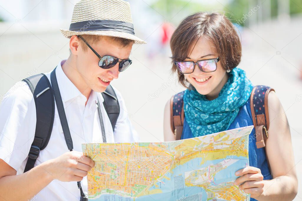 Trendy young couple in town with touristic map