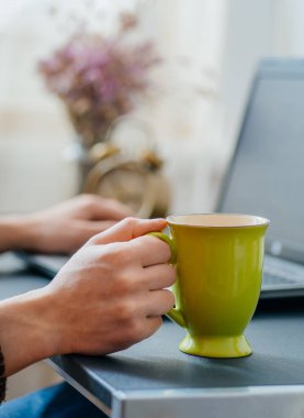 Ofiste dizüstü bilgisayarda çalışmak ve kahve içmek.