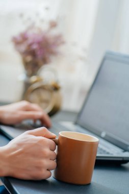 Laptop, kahve fincanı ve çiçekli ofis masası.. 