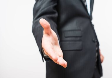 El sıkışmak için uzanan bir iş adamının yakın çekimi. Kırpma yolu da dahil olmak üzere beyazda izole edilmiş. İnce çizgili takım elbiseli bir iş adamı..