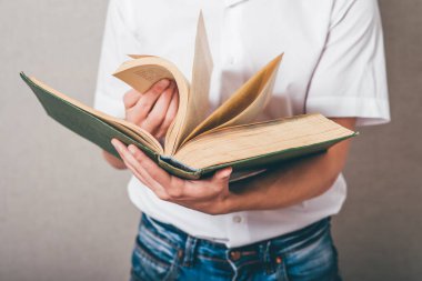 Gözlüklü adam büyük bir kitap okuyor.
