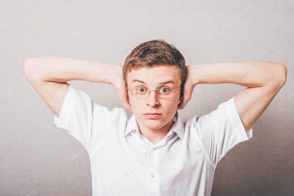 bespectacled man covers his ears with his hands