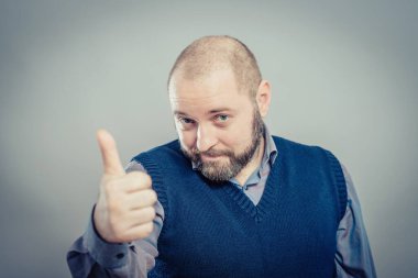 Genç adam gülümsüyor ve baş parmağını kaldırıyor.