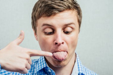 Genç adam işaret parmağını dilinde gösteriyor.
