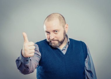 Genç adam gülümsüyor ve baş parmağını kaldırıyor.