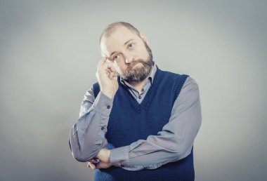 Genç adam parmağını şakağına koyduğunu düşünüyor.