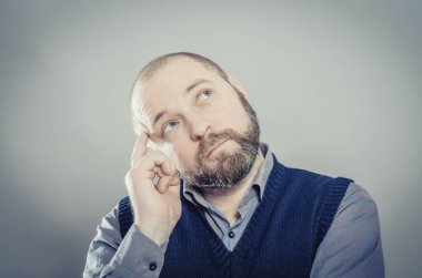 Genç adam parmağını şakağına koyduğunu düşünüyor.