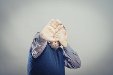 Genç adam yüzünü kapatarak gülüyor.