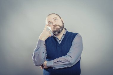 Genç adam parmağını şakağına koyduğunu düşünüyor.