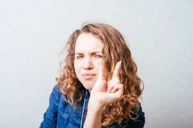 Kıvırcık kız küçük bir parça gösteriyor. Gri arkaplan.