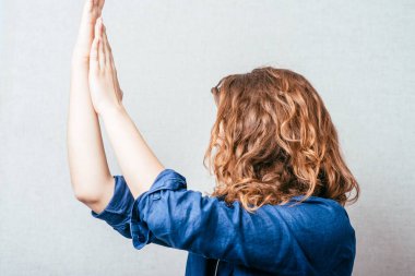 Kıvırcık kadın neşeyle ellerini çırpıyor, dans ediyor. Gri arkaplan.