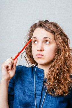 Kadın kalemle bir şey düşünüyor.