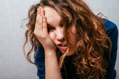 Kıvırcık kız kendini iyi hissetmiyor. Gri arkaplan.