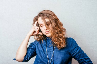 Kıvırcık kız üzgün düşünüyor. Kafasındaki el. Gri arkaplan.