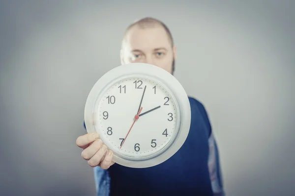 灰色の背景に時計を保持している若い男の肖像 — ストック写真