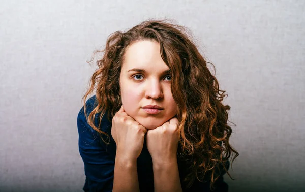 Gekruld Meisje Verdrietig Denken Hand Haar Hoofd Grijze Achtergrond — Stockfoto