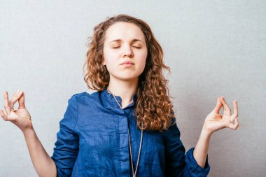 Kadın meditasyon yapıyor, dinleniyor. Gri arkaplan