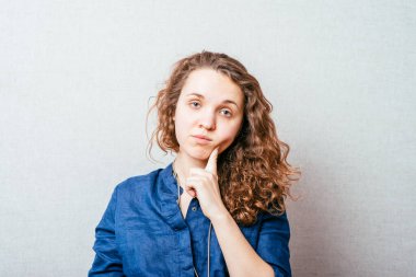 Genç bir kadın hayal kuruyor, hayal kuruyor, el pençe divan bir yere bakıyor.