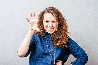 Kıvırcık kız çok korkutucu bir el. Gri arkaplan.