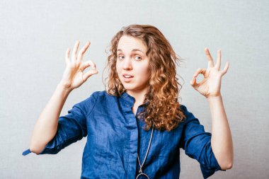 Bir kadın iyi bir jest gösterir. Gri arkaplan