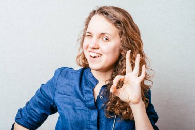 Gri arka planda bir kadın jest yapar..