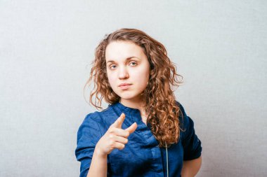 Kadın parmağını ileri uzattı. Gri bir arkaplanda.