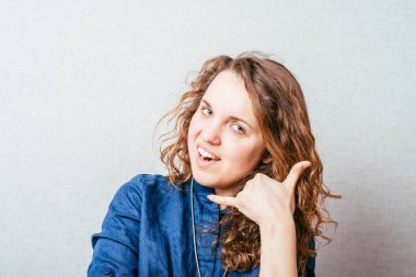 Kıvırcık Kız şakacı bir şekilde beni ara. Gri arkaplan.