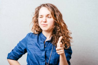 Kadın işaret parmağını öne doğru gösteriyor. Gri arkaplan