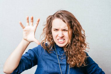 Kıvırcık kız çok korkutucu bir el. Gri arkaplan.