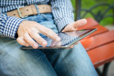 Genç adam dijital tablet kullanarak eğleniyor.