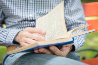 Adam okuyor. Kitap onun elinde..