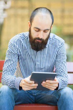 Adam tablet bilgisayar kullanıyor. Elinde modern bir alet..