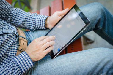 Genç adam dijital tablet kullanarak eğleniyor.