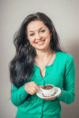 Gri arka planda bir fincan kahve tutan güzel kız.