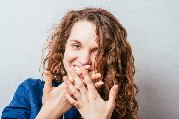 Curly Smiling Woman Covers Her Mouth Her Hands Gray Background — Stock Photo, Image