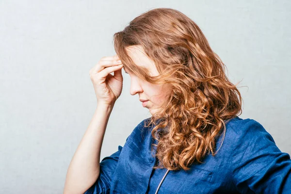 Kadın düşünüyor, elleri başının üstünde. Gri bir arkaplanda.