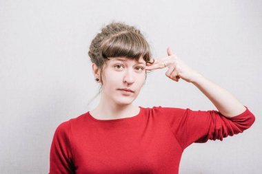 İntihar jestli kadın, silahı teslim et. Gri bir arkaplanda.