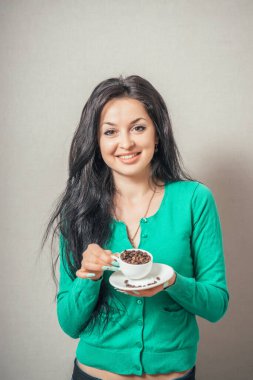 Gri arka planda bir fincan kahve tutan güzel kız.