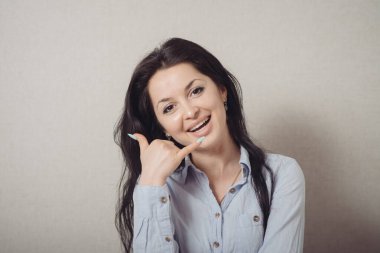 El kol hareketi yapan kadın beni ara. Gri bir arkaplanda.