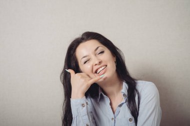 El kol hareketi yapan kadın beni ara. Gri bir arkaplanda.