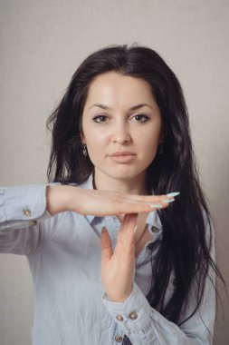 Duran bir kadın, olamaz, bir mola. Gri bir arkaplanda.