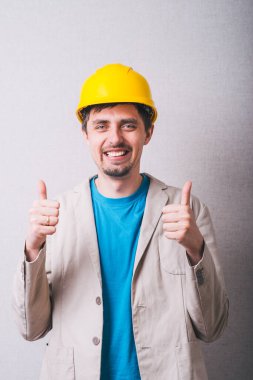 İnşaat kasklı bir adam baş parmağını kaldırıyor.