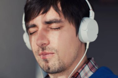 Müzik dinleyen genç bir adamın portresi.