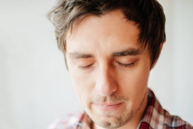 Yakışıklı, barışçıl, huzurlu, rahat görünen, kulaklarını kapatan genç iş adamının kapalı gözleri, soyutlanmış beyaz bir arka plan portresi. Şeytani kavram duymuyorum. İnsani duygular, yüz ifadeleri