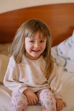 Bebeğim pijamalarıyla yatakta oturuyor.