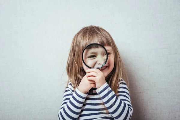 Beautiful little girl looking through a magnifying glass