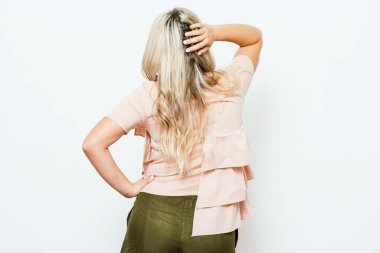 Arkadan bakan kadın uzun saçlı, sırtı beyaz arka planda soyutlanmış.