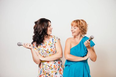 İki mutlu kadın mikrofonlara şarkı söylüyor ve eğleniyorlar.