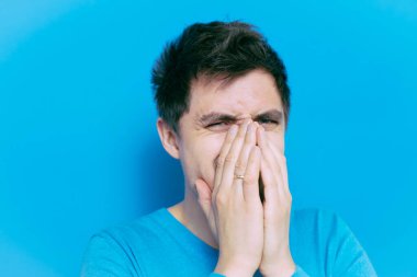 Adam gülüyor ve ağzını kapatıyor.